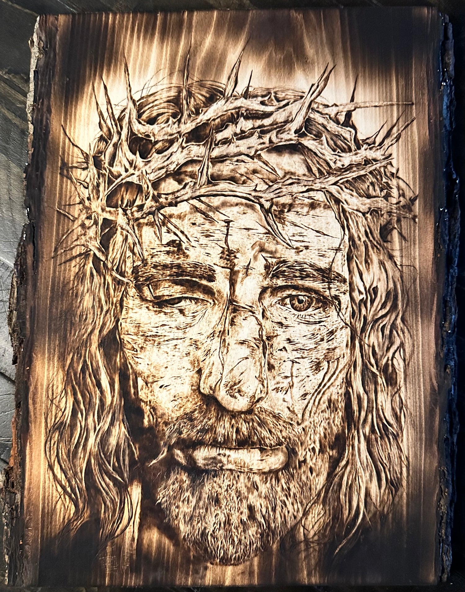 This image features a striking wood burning artwork titled "Jesus (Original Wood Burning)". The piece beautifully captures the portrait of Jesus, emphasizing His facial features and the crown of thorns he wears.